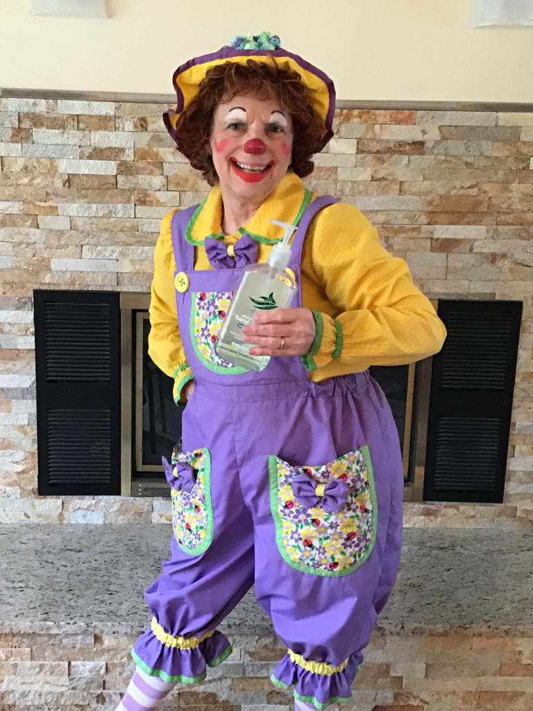 Rainbow the Clown holding a bottle of hand sanitizer