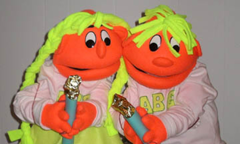 Two similarly-colored puppets holding candles