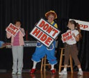 Rainbow and two children hold signs that say "Don't Hide"